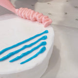 Person decorating a cake with blue and pink icing