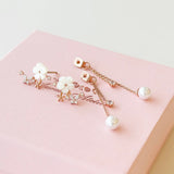 A pair of rose gold floral hair clips with white faux pearls and clear rhinestones, displayed on a textured pink gift box.